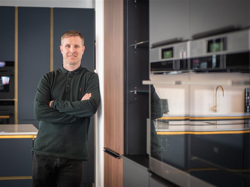 Man standing confidently in a modern kitchen, showcasing sleek cabinetry and high-end finishes, reflecting Highline Homes' commitment to exceptional design and craftsmanship.